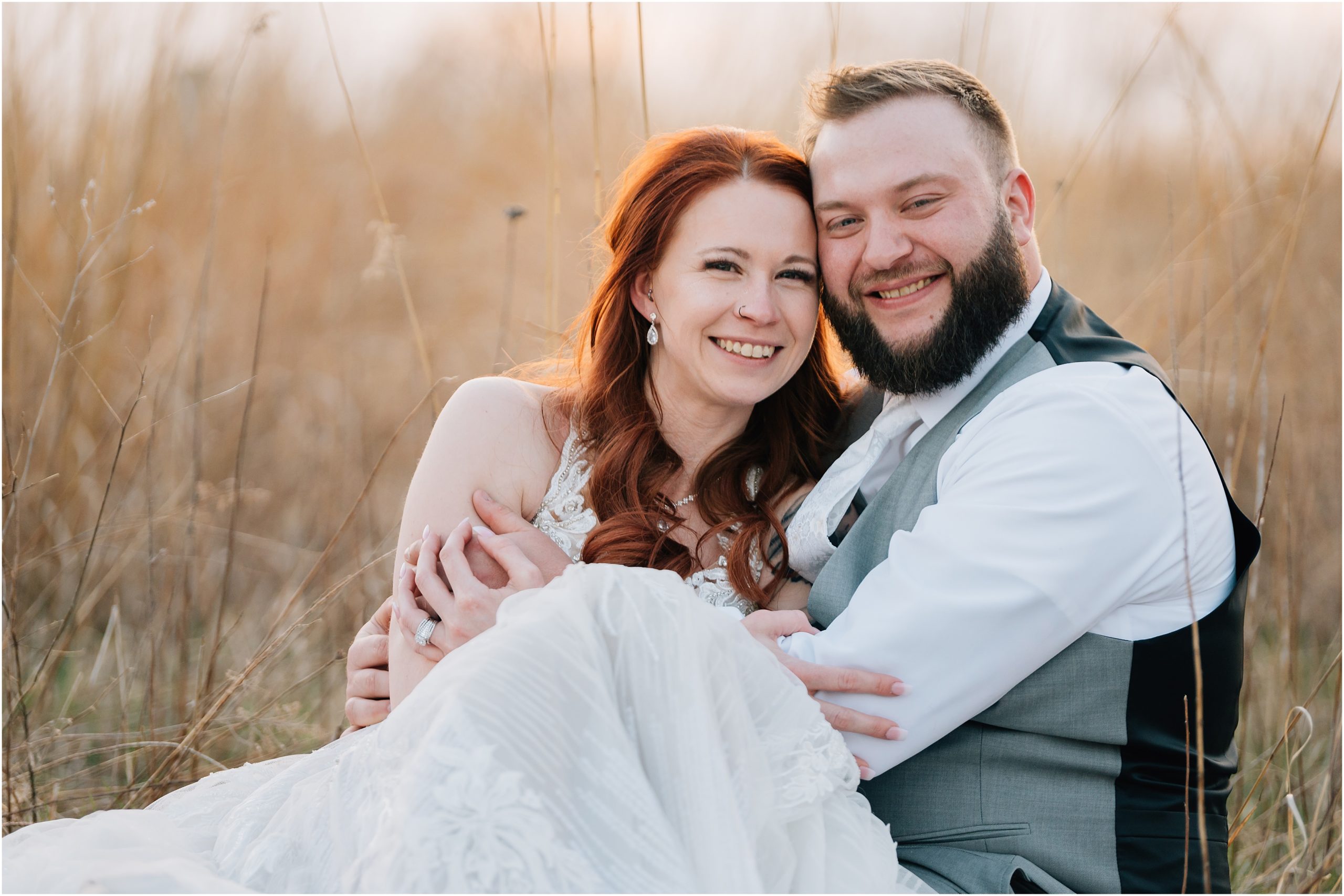 Couple sits in a field and smiles at the camera at Honey Creek Resort on Rathbun Lake. Photo is by Anna Brace who specializes in Omaha Wedding Photography