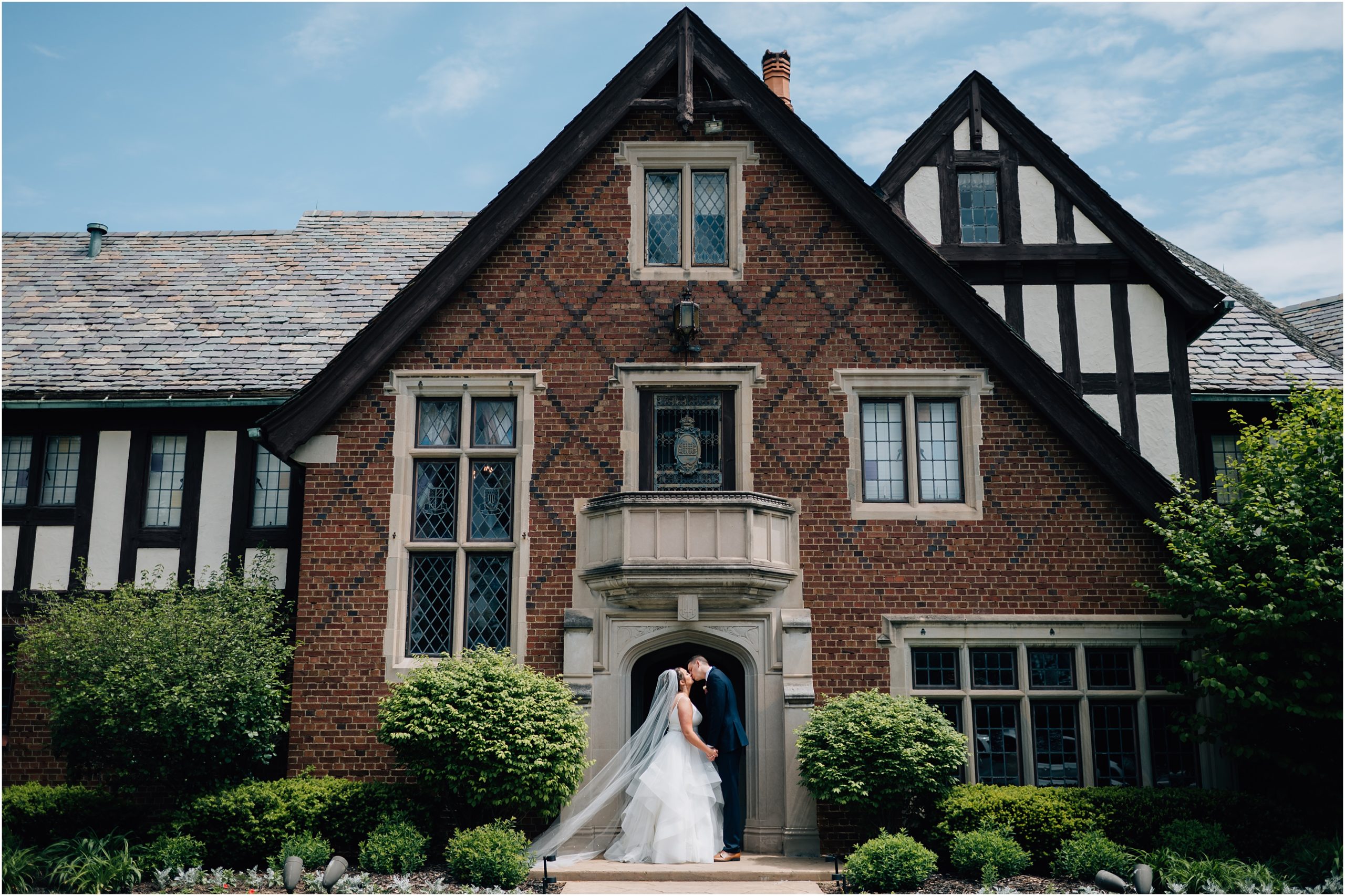 Bride and Groom share a kiss in front of Rollins Mansion. A tudor style hisotrical mansion in Des Moines Iowa. Photo by Anna Brace, who specializes in Omaha NE wedding Photography.