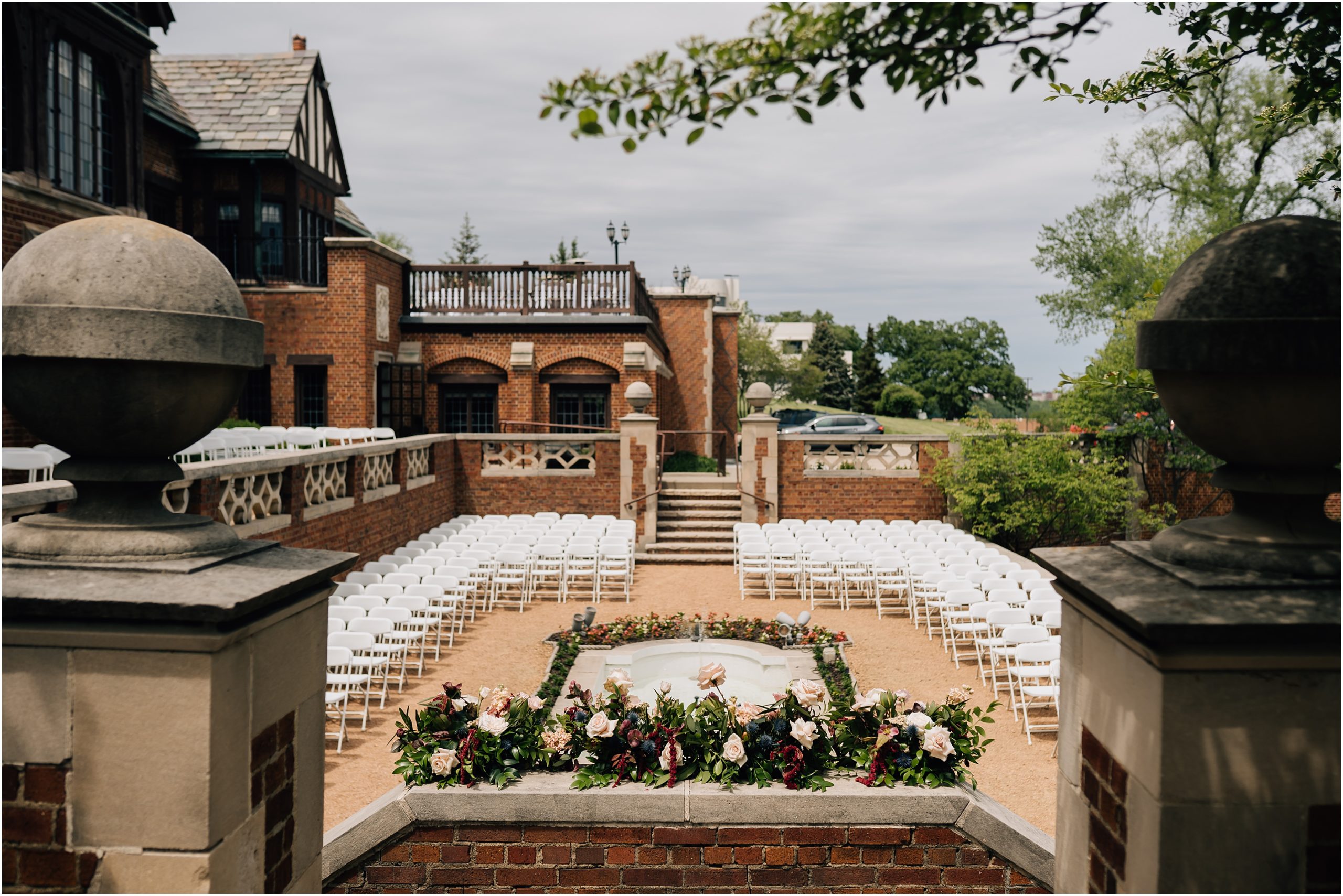The courtyard at Rollins Mansion from above. There's white chairs all around and florals sitting on the brick borders. Photo at Rollins Mansion by Anna Brace, who specializes in Omaha Nebraska Wedding Photography