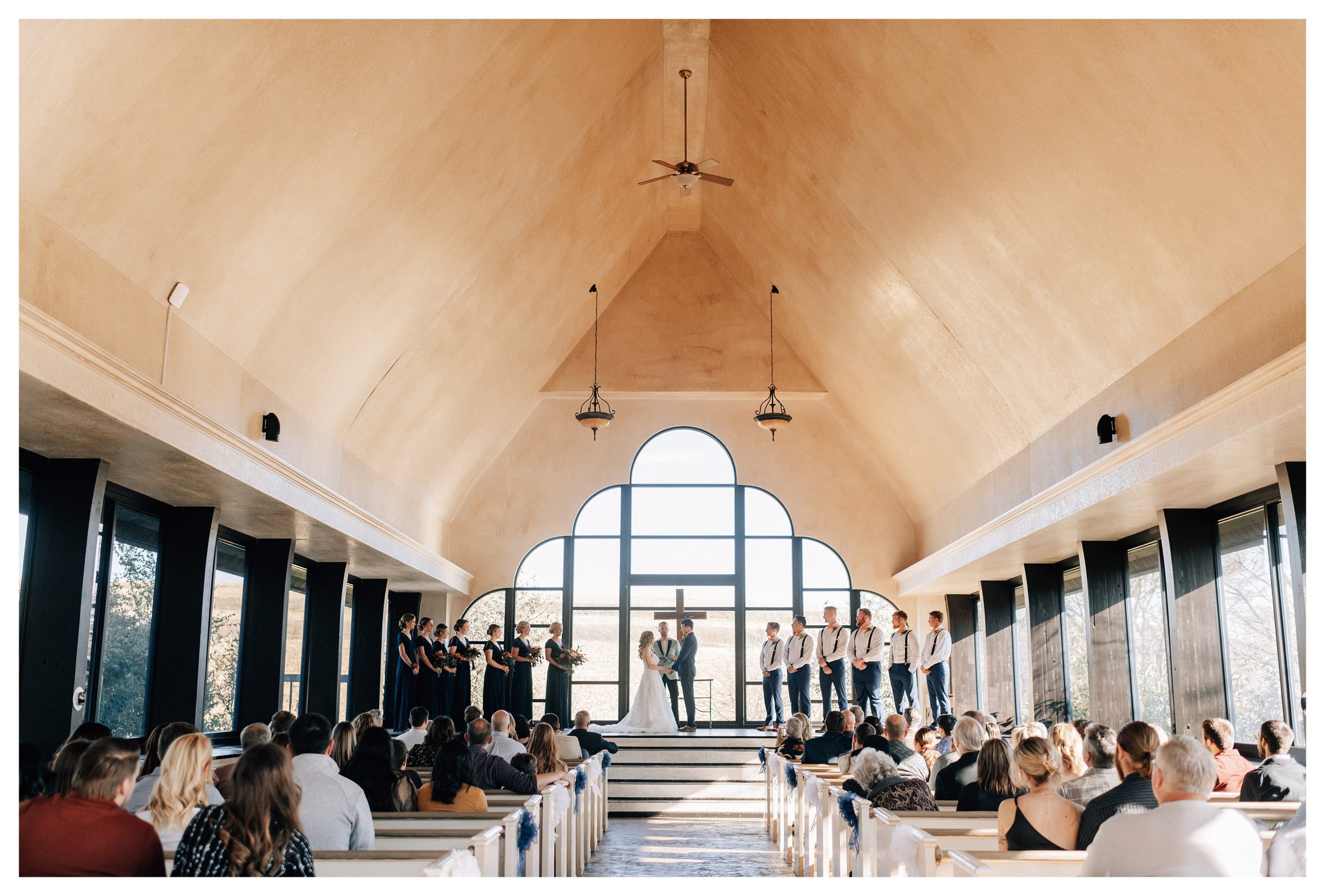 Bride and Groom stand at the front of The Willow Creek Glass Chapel, a wedding venue in Omaha. Photo by Anna Brace, an Omaha NE Wedding Photographer. 