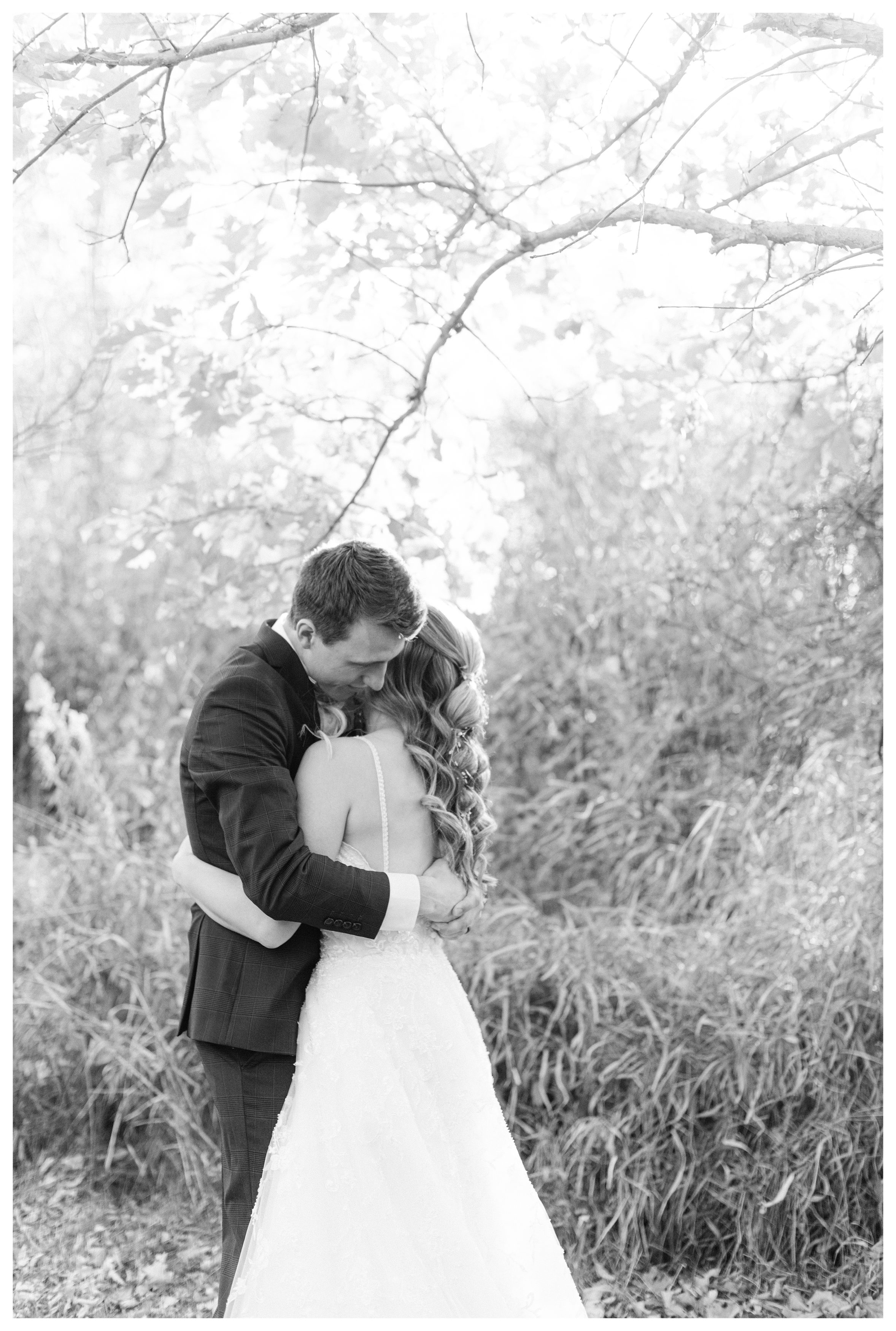 Black and White photo of bride and groom hugging at The Willow Creek Glass Chapel. Photo by Anna Brace, an Omaha Nebraska Wedding Photographer. 