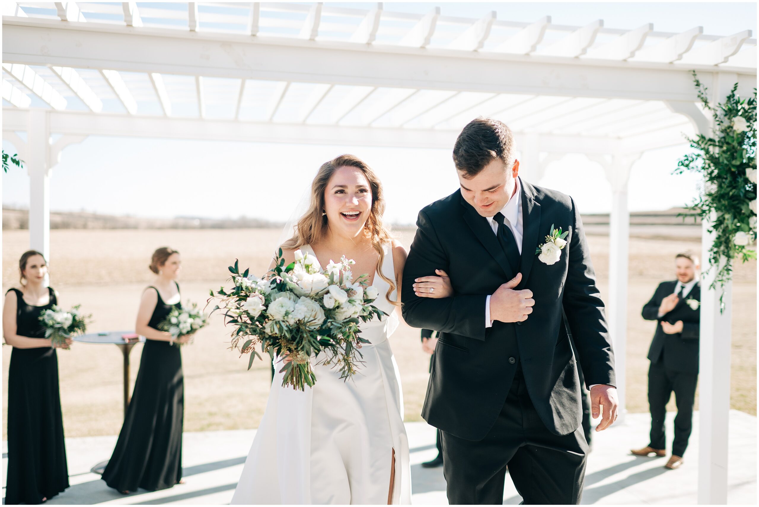Bride and Groom walk arm in arm back down the aisle at the Palace Barn in Treynor Iowa. Photo by Anna Brace, an Omaha NE Wedding Photographer.