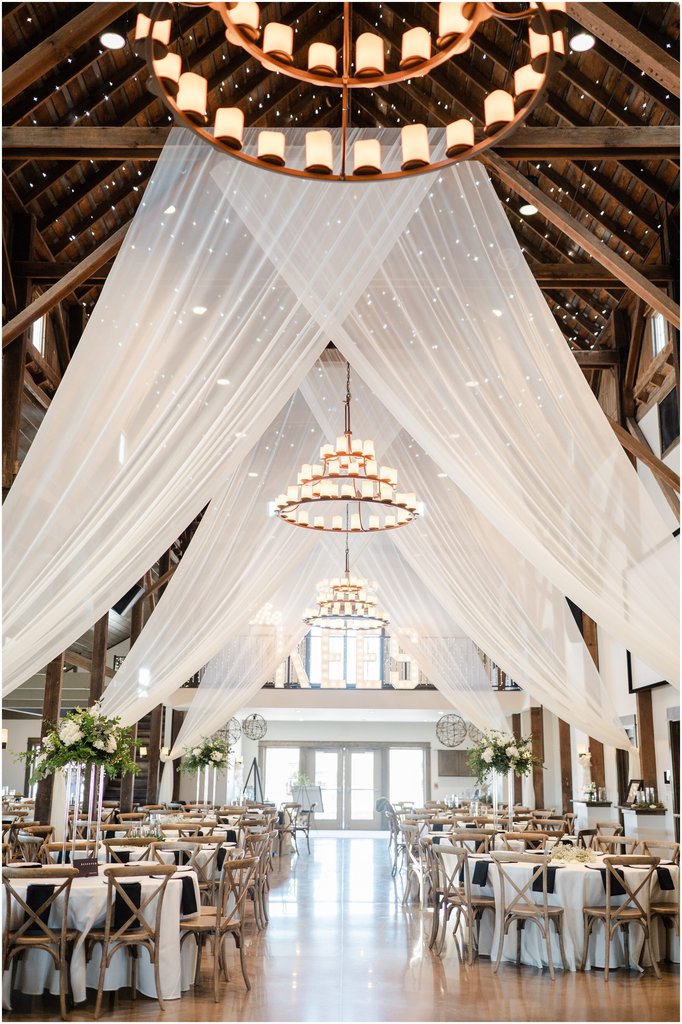 The Palace Event center's reception space with white drapes and greenery everywhere. Photo by Omaha wedding photographer, Anna Brace. 
