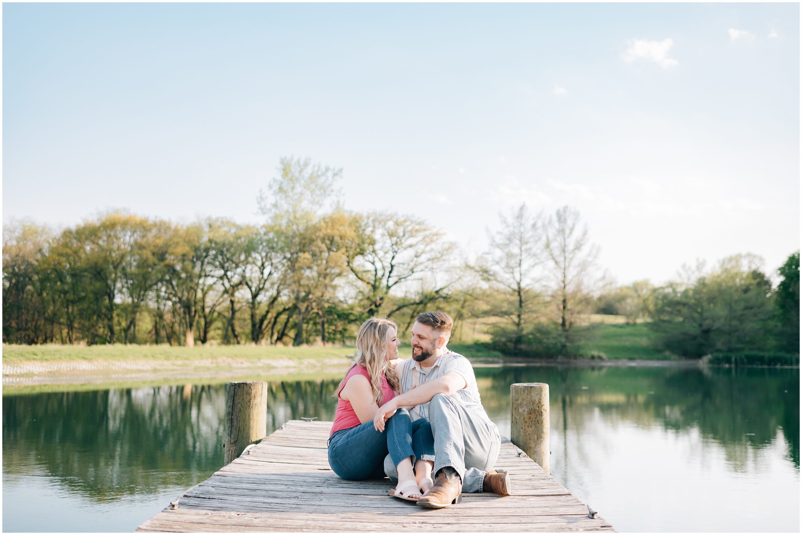 Engaged couple sits on a boat dock and talks. Photo by Anna Brace, an Omaha wedding photographer.
