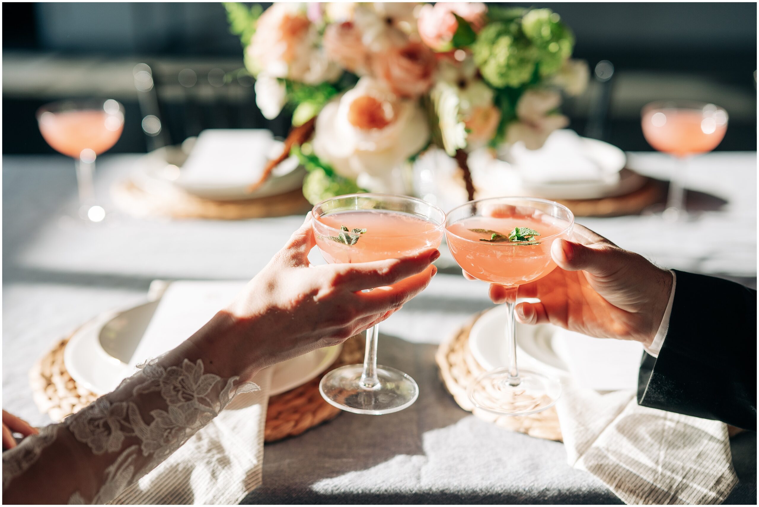 Bride and groom clink glasses filled with pink lemonade and a sprig of mint at The Stables at Copper Ridge. Photo by Anna Brace, an Omaha NE Wedding Photographer.