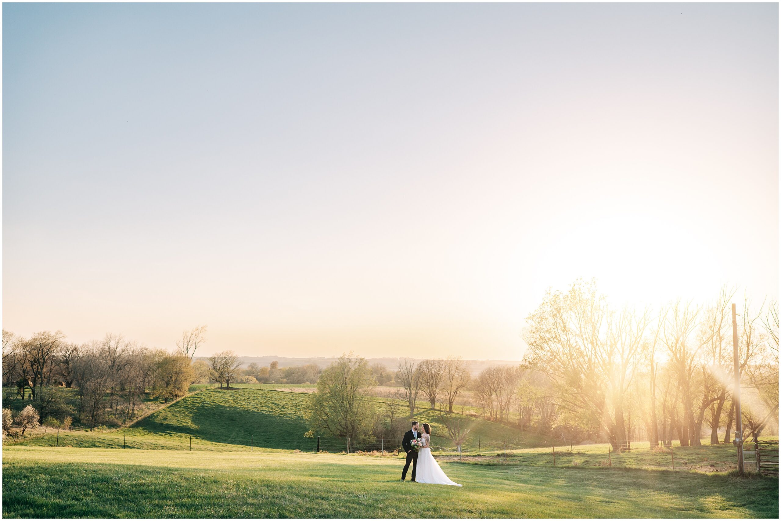 Bride and groom stands on top of a hill at The Stables at Copper Ridge while the sun sets behind them. Photo by Anna Brace, an Omaha Nebraska Wedding photographer.